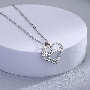 Silver Mama heart necklace with hollow design and light blue gemstones on white stand