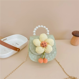 Détail macro du mini sac de selle avec dentelle, décor fleuri et poignée perle