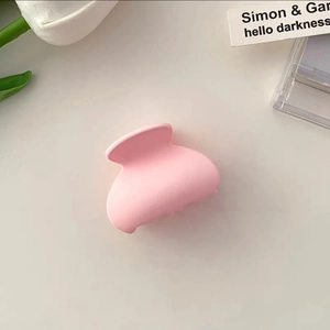 Close-up of a matte pink hair claw clip on white background with a white tulip decoration