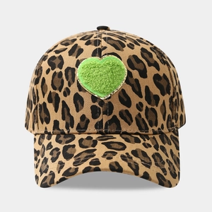 Detail of leopard print baseball cap featuring a green plush heart with gold embroidery