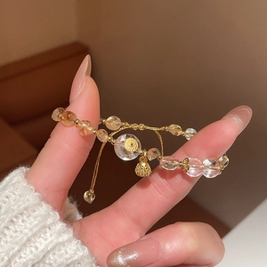 Detailed macro shot of beaded crystal bracelet with golden bell charm on wrist