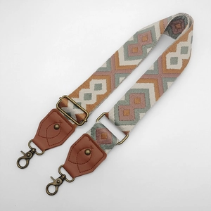 Detalle de correa de bolso tejida bohemia con cuero marrón y ganchos de metal bronce