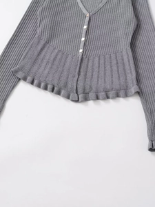 Detail of grey ribbed knit cardigan featuring ruffle hem and white resin buttons