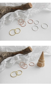 Close-up of minimalist S925 silver, gold, and rose gold slim rings on a wooden display stand