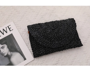 Dettaglio della pochette in paglia intrecciata nera con patta a busta e anello a D in metallo