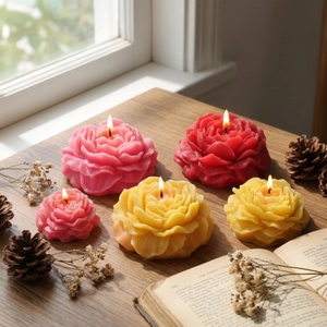 Peony and rose shaped scented candles in pink and red on a rustic wooden table