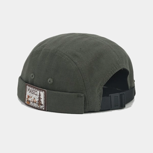 Detail of adjustable strap and vintage patch on green brimless docker miki hat