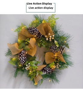 Close-up of lighted Christmas wreath with pine cones, burlap bow and warm LED lights