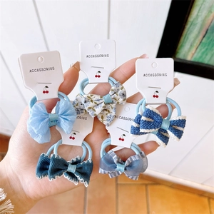 Detail showing five blue bow hair scrunchies with floral and striped fabric patterns