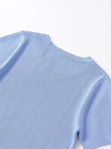 Detail shot of the light blue rib-knit neckline and fine stitching on the shoulder seam