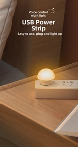 Voice control USB night light with frosted shade plugged into power strip on a desk
