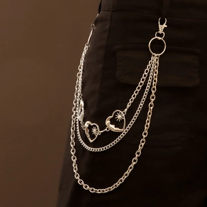 Detail of silver multilayer waist chain with heart and star pendants on black trousers