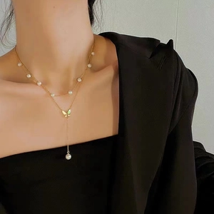 Elegant double-layered gold necklace with white pearls and butterfly fringe pendant