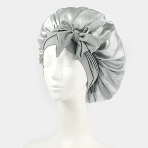 Macro detail of silver satin sleep cap featuring a smooth texture and large bow decoration