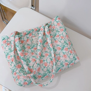 Macro view of floral quilted cotton tote bag featuring delicate rose patterns and fabric label