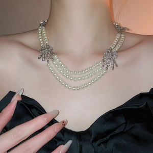 Close-up of elegant multilayer pearl necklace with silver bowknot on a model neck