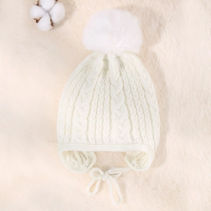 Detailed knit texture of white baby winter hat with plush pompom on soft background