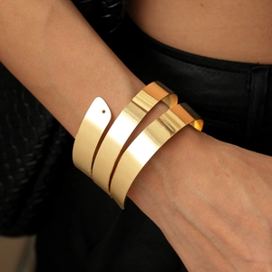 Macro view of minimalist golden triple-layer spiral arm cuff on black background