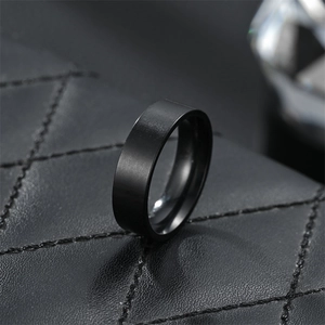 Macro shot of matte black stainless steel flat ring on textured black leather base