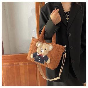 Detail of brown quilted kids tote bag featuring a cute bear patch and beige shoulder strap