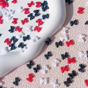 3D resin bowknot nail charms in red, white and black colors on a white display tray