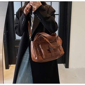 Brown leather crossbody bag shown on model with vintage flap and buckle closure design