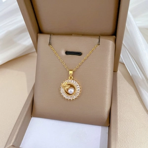 Detailed view of gold necklace with pearl and leaf pendant in luxury gift box display