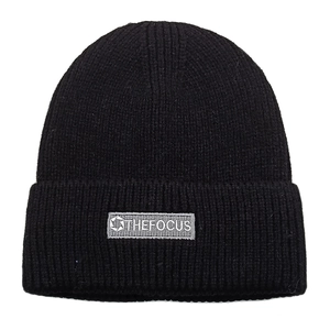 Close-up of black ribbed knit beanie with grey Thefocus woven label detail