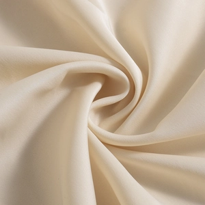 Macro shot of satin fabric showing draped spiral texture and glossy beige twill detail