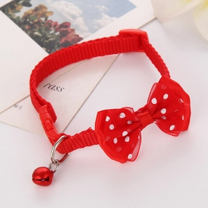 Close-up of red nylon pet collar with white polka dot mesh bow and metal bell detail