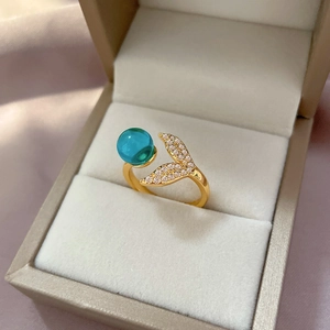 Detail of gold mermaid tail ring with blue crystal bead and pavé diamonds in a gift box
