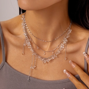 Detailed view of layered silver necklace with irregular transparent crystal beads on model