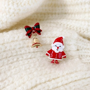 Close-up of Santa Claus and Christmas bell earrings on a white knitted fabric background