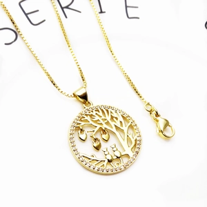 Detailed macro view of a gold-plated tree of life pendant with heart and owl accents