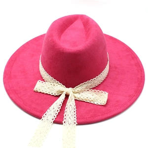 Detail of rose red wide brim fedora hat featuring ivory lace ribbon and decorative bow