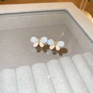 Détail de boucles d'oreilles papillon pailletées dégradé bleu sur une boîte à bijoux