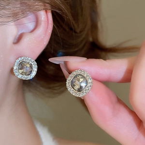 Detailansicht goldener Ohrstecker mit grauem Stein und Zirkonia-Besatz am Ohr getragen