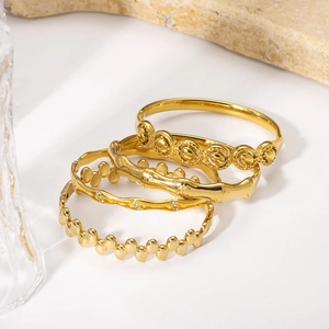 Ensemble de quatre bracelets ouverts en acier doré avec motifs bambou et perles