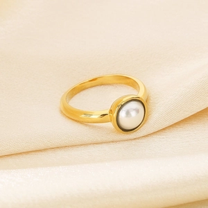 Detailaufnahme des minimalistischen Perlenrings in Gold auf elegantem Seidenhintergrund