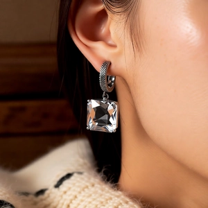 Detail showing square cut crystal earring with spiral silver ring on model
