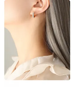 Close-up of gold titanium hoop earrings with multi-row pavé zircon on a female model