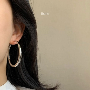 Detailed view of 5cm diameter silver hoop earrings shown on a female model