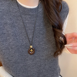 Detail der Vintage Harzkette mit goldener Perle an einem dunkelbraunen Ringanhänger