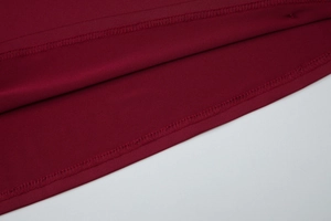 Close-up of the professional hem stitching on a dark red bodycon dress fabric