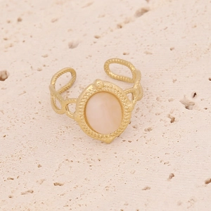 Macro shot of gold ring with pink opal inlay and twisted rope texture on stone background