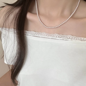 Gros plan d'un collier de perles de style français avec fleurs porté sur la clavicule