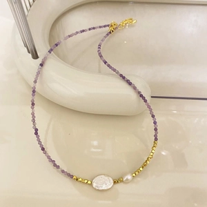 Detail of purple tourmaline and freshwater pearl necklace on a white ceramic tray