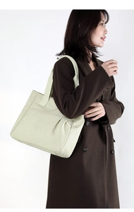 Detailed side view of off-white canvas tote bag with pleated bottom on a model
