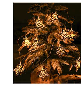 Macro detail of warm LED star-shaped lights nestled in snowy Christmas tree branches