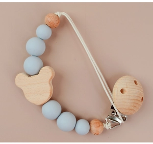 Detail of wooden bear pacifier clip with silicone beads and cotton cord in grey and natural